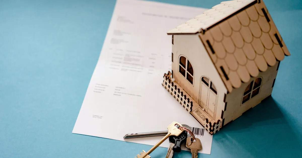 wooden house with keys and financial documents all on a table