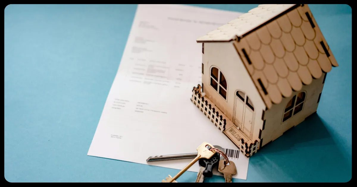 wooden house with keys and financial documents all on a table