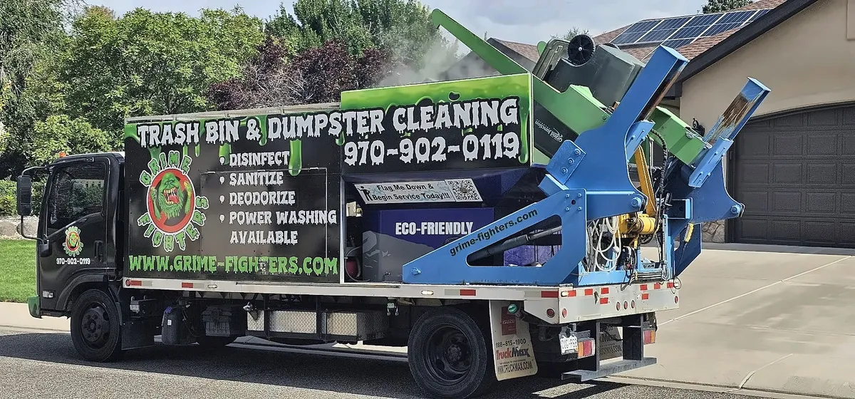 Side of the Grime Fighters truck with a trash bin raised on the lift