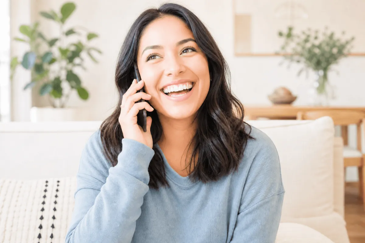 Person laughing warmly during a phone call at home