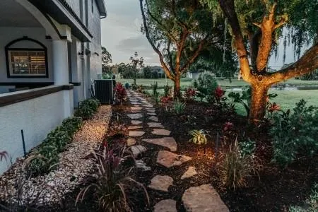 Backyard pathway with decorative landscape lighting near home exterior