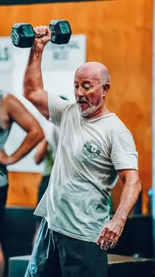 Man and woman performing kettlebell swings in gym.