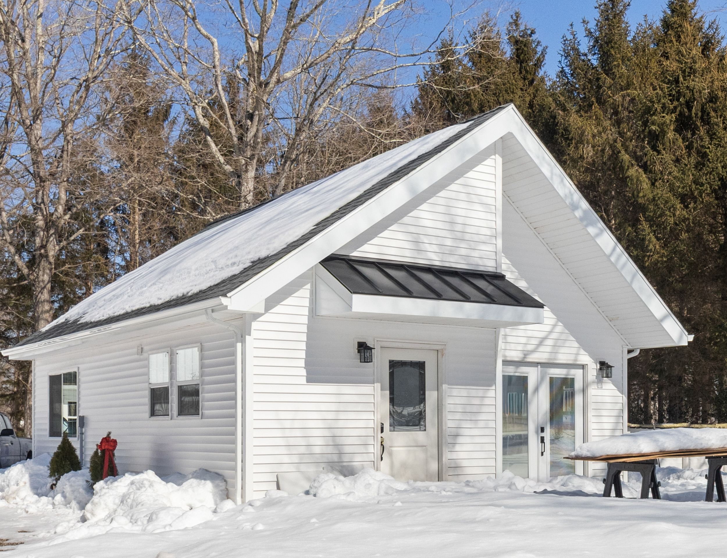 White ADU with a steep metal roof surrounded by snow.
