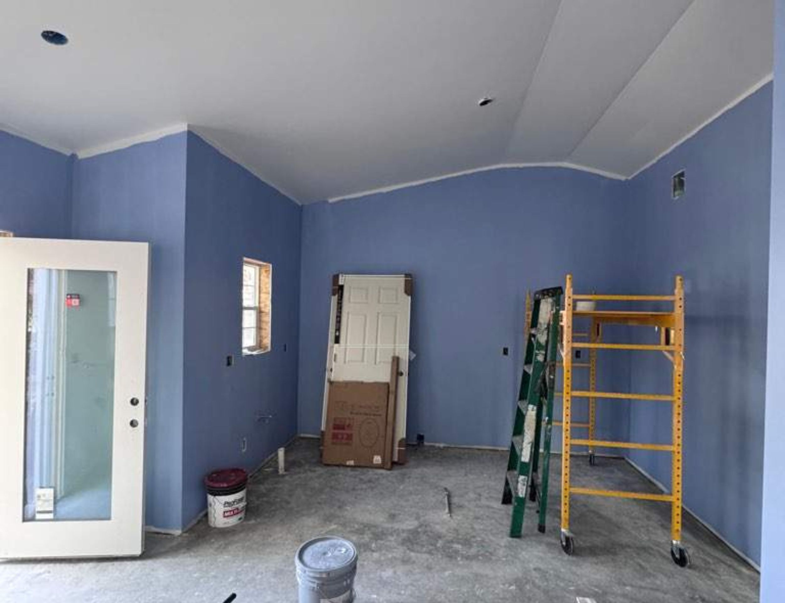 ADU interior under construction with blue walls, tools, and scaffolding.