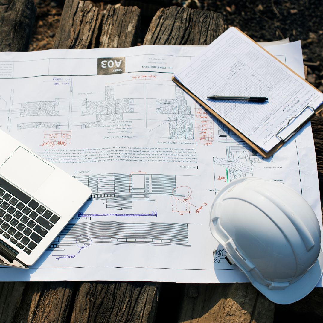 ADU construction schedule planning with blueprints, laptop, clipboard, and hard hat.