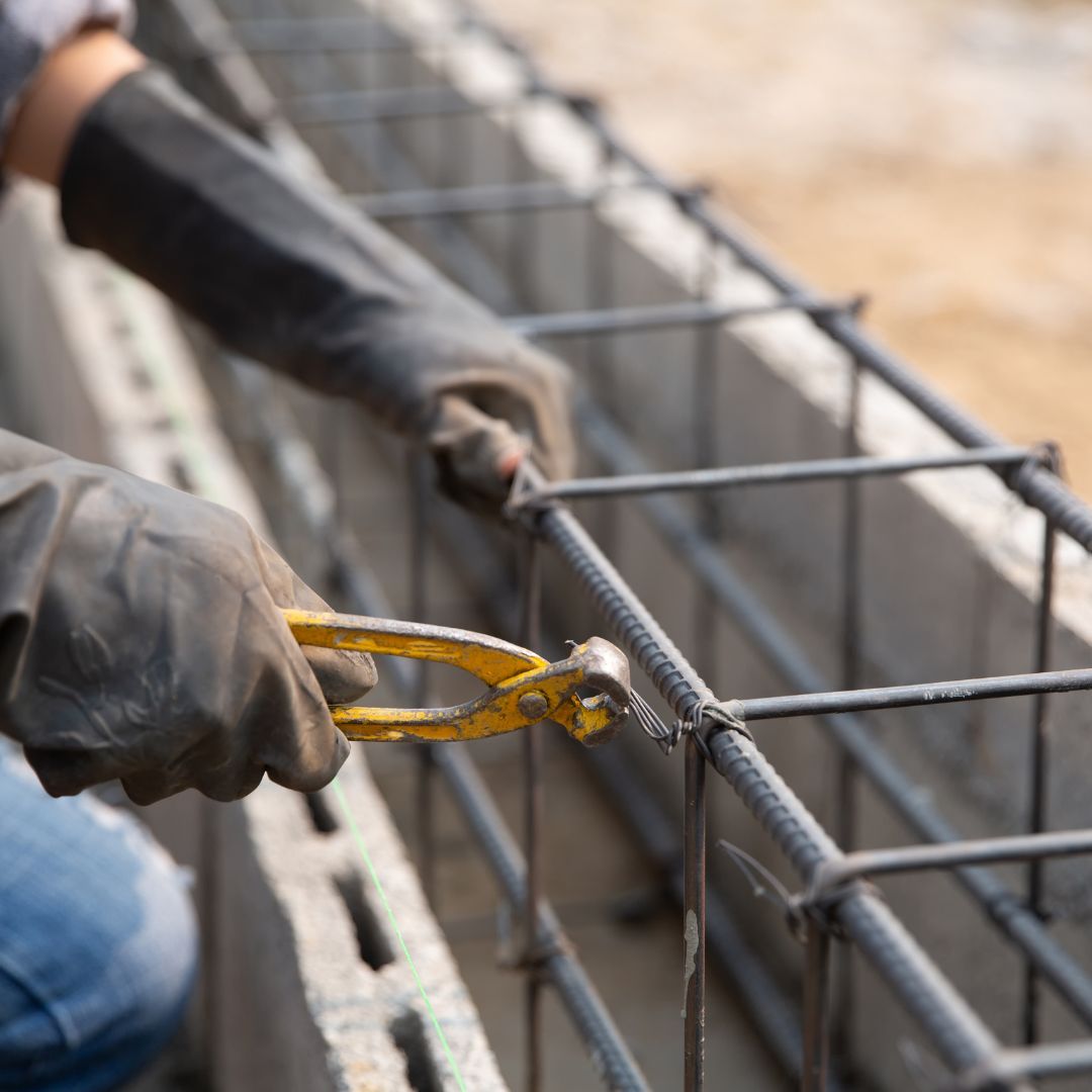 Worker securing steel rebar for an ADU concrete foundation.