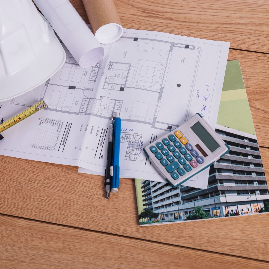 ADU design plans with blueprints, calculator, pen, and material samples.