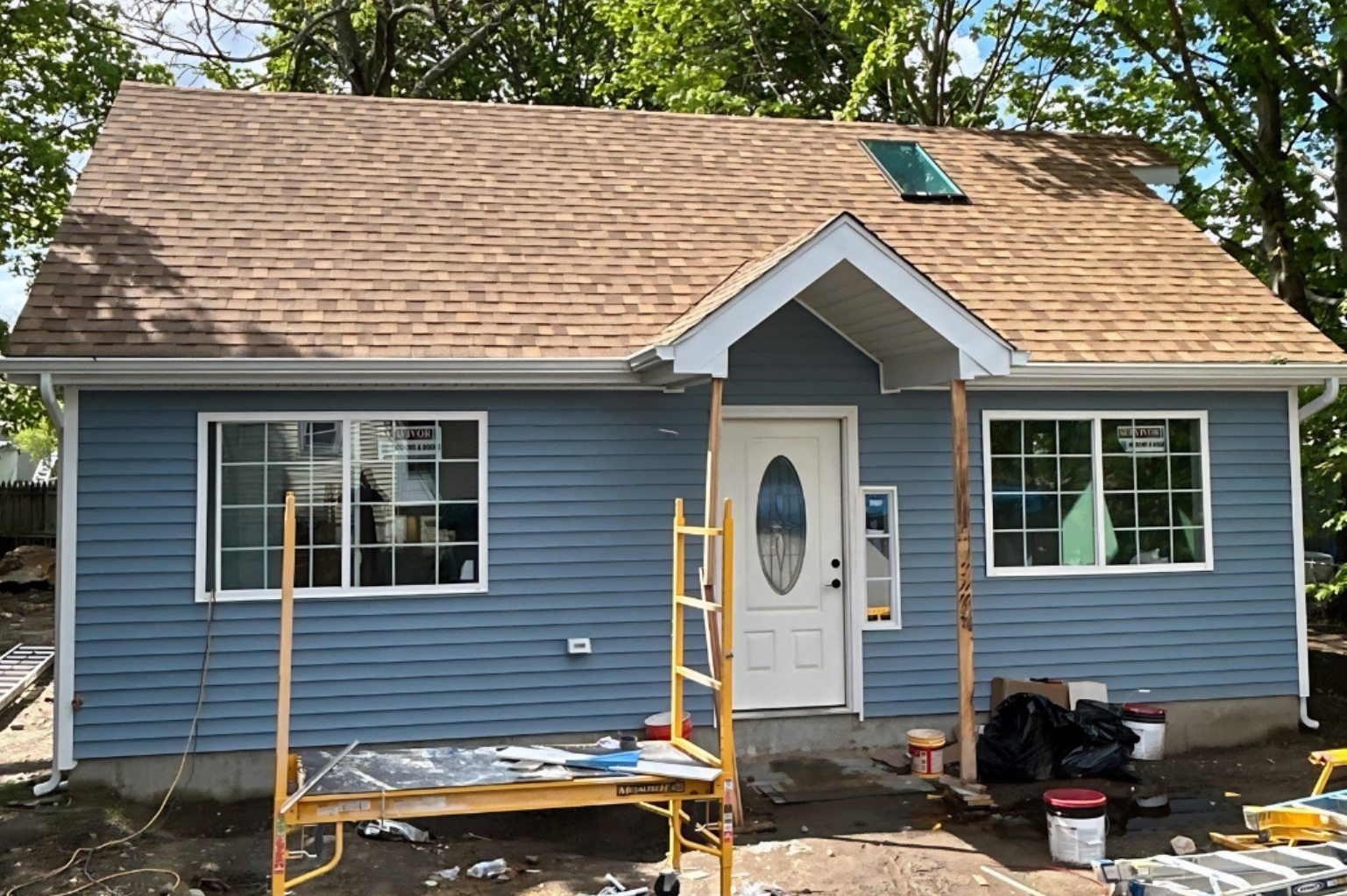 Blue detached ADU under construction with a front entry and large windows in Groton, Connecticut.