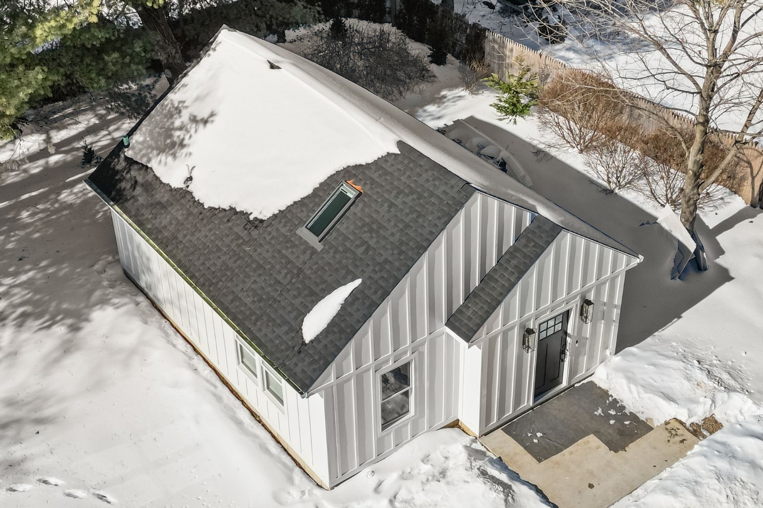 Gray single-story ADU with a modern gable roof, viewed from above, surrounded by sno.