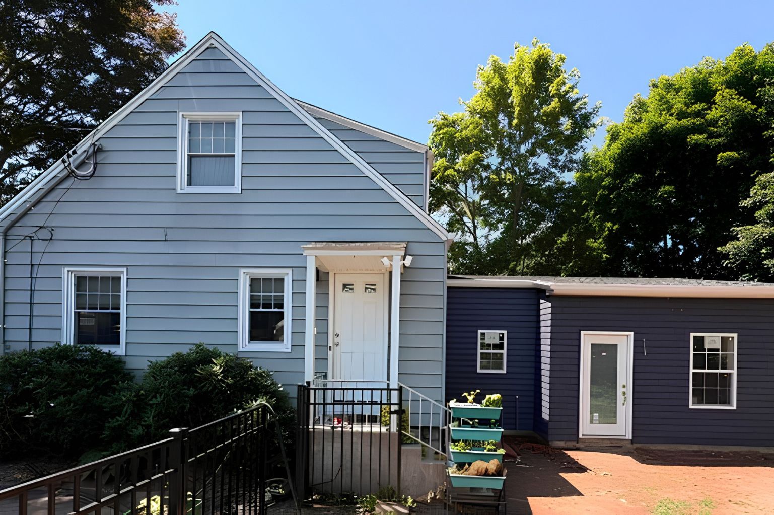 Blue single-story ADU with white trim, a covered front entrance, and a connected modern addition