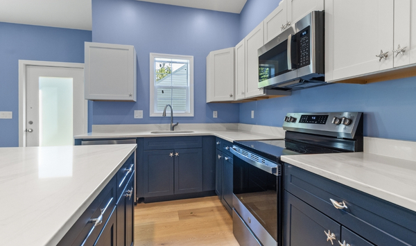 Attached ADU Light blue Connecticut home with a dark blue attached ADU addition, separate entrance, windows, and fenced walkway.