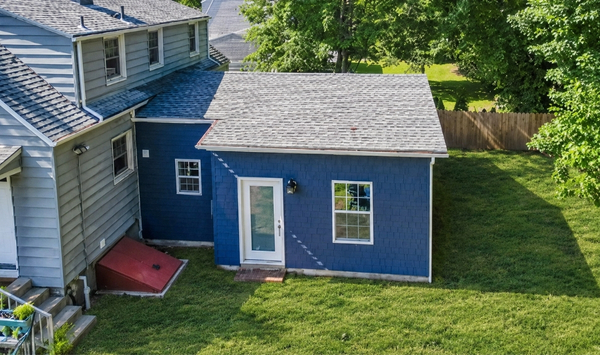 Blue single-story ADU with white trim, a covered front entrance, and a connected modern addition