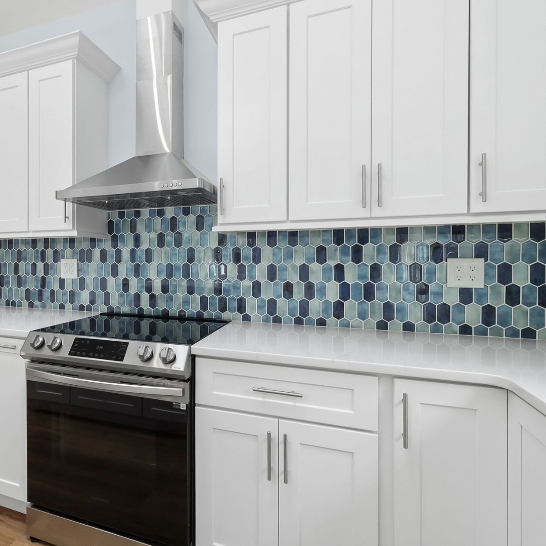 Modern ADU kitchen with white shaker cabinets, stainless steel range and hood, and blue hexagon tile backsplash.
