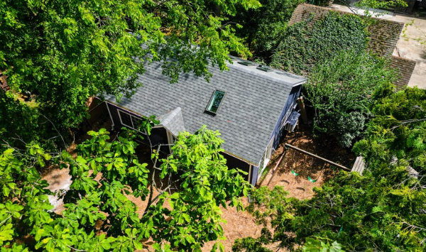 Aerial view of a small residential building surrounded by mature trees, illustrating backyard ADU site planning considerations.