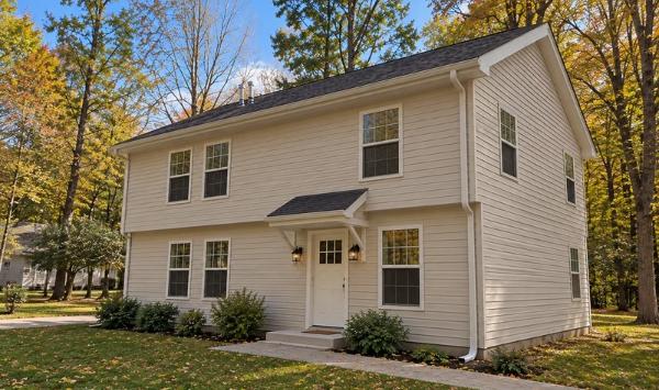 Conceptual two-story ADU design in Connecticut with beige siding, white trim, a covered entrance, and a dark shingle roof.