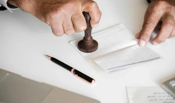 Close-up of a person stamping a document, illustrating the ADU building permit approval process.