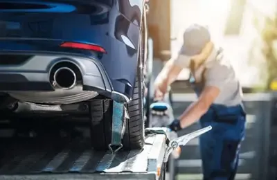 Auto, von hinten zu sehen, wird auf einem Abschlepper von Mann mit Kappe fixiert