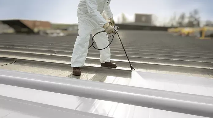 Freshly coated white silicone membrane roof on a flat commercial building under clear skies.