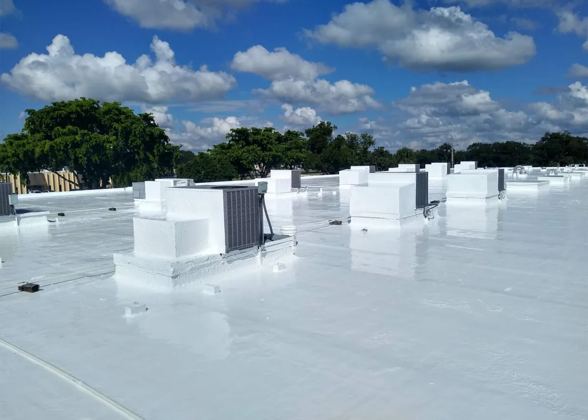 Roofers installing a large-scale commercial metal roof with safety harnesses on structural steel framing.