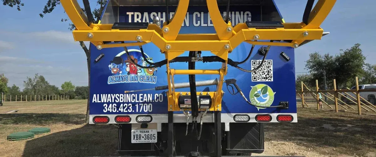 A back view of a blue trash cleaning truck with yellow hydraulic arms, branding, a QR code, and a Texas license plate.