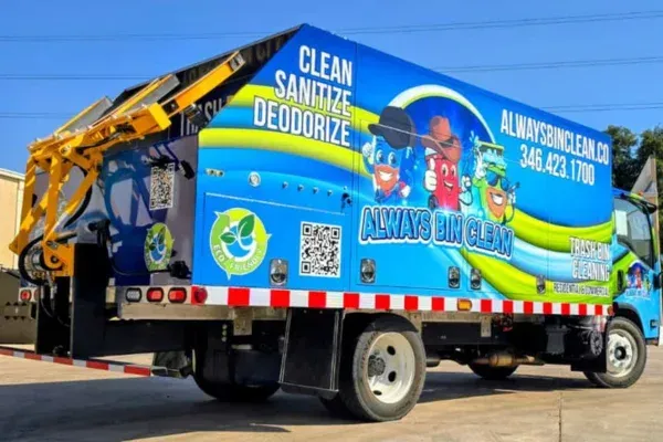 Rear side view of a vibrant blue bin cleaning truck with 'Always Bin Clean' branding and cartoon characters.
