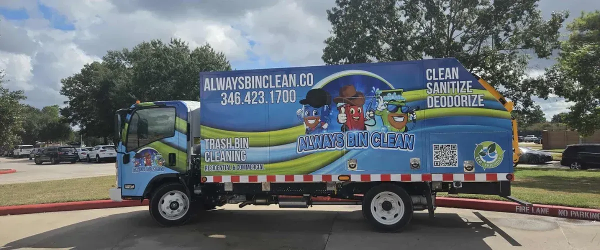 A blue and green 'Always Bin Clean' trash bin cleaning truck parked outdoors with cheerful bin mascots.
