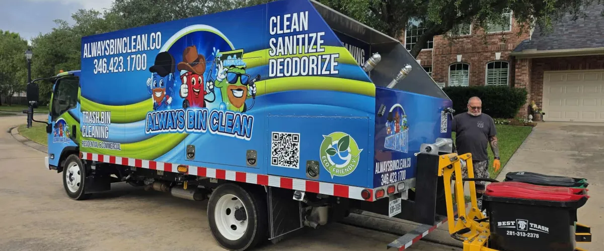 A brightly colored blue 'Always Bin Clean' trash bin cleaning truck with a man standing by its rear lift mechanism.
