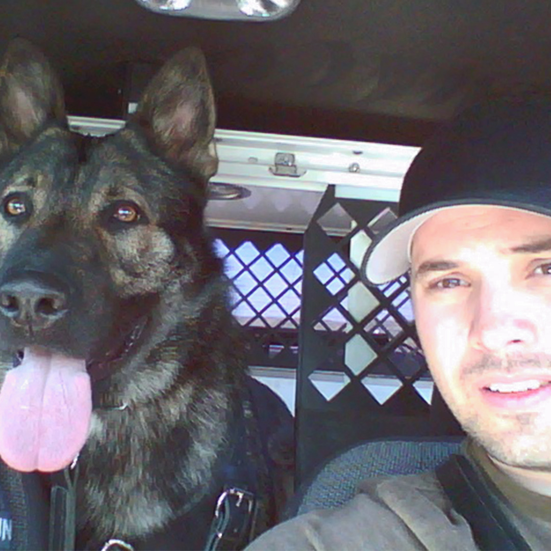 man and a dog in a police car