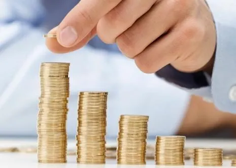 A hand placing a coin on growing stacks of coins