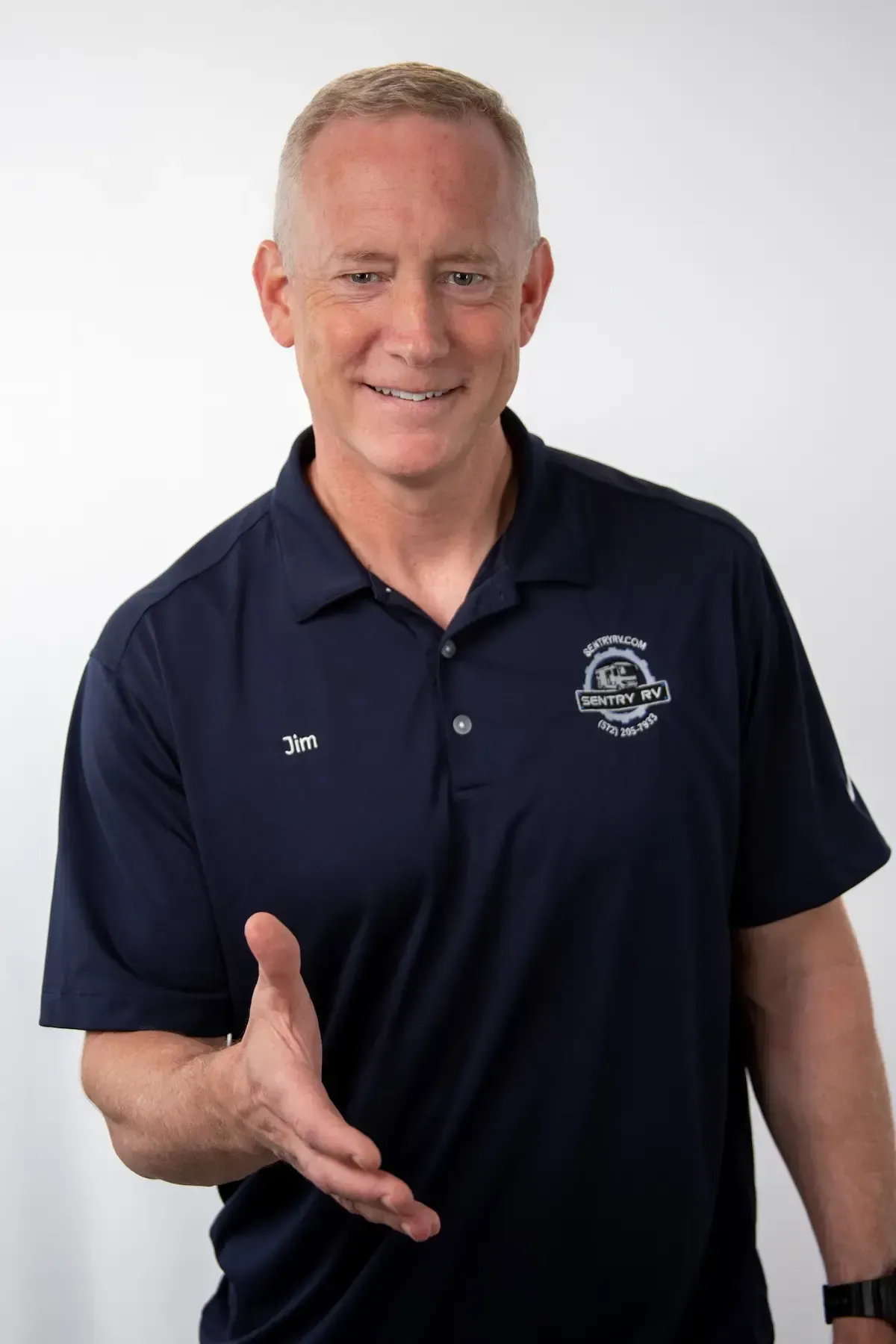 Smiling man in a navy polo shirt with "Sentry RV" logo, extending hand for a handshake, representing trust and service in mobile RV repairs.