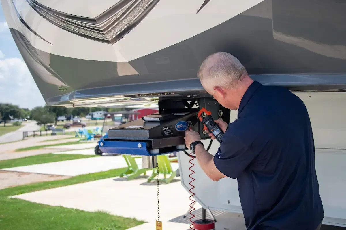 Technician inspecting RV fifth wheel hitch using tools, emphasizing SentryRV's mobile rv repair services