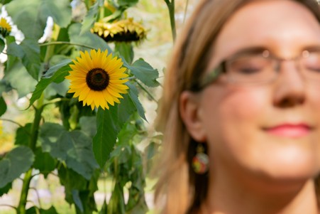 Calm self-care themed image of Rachel standing in front of sunflowers representing emotional regulation strategies for neurodivergent people, including mindfulness, rest, support and stress management.