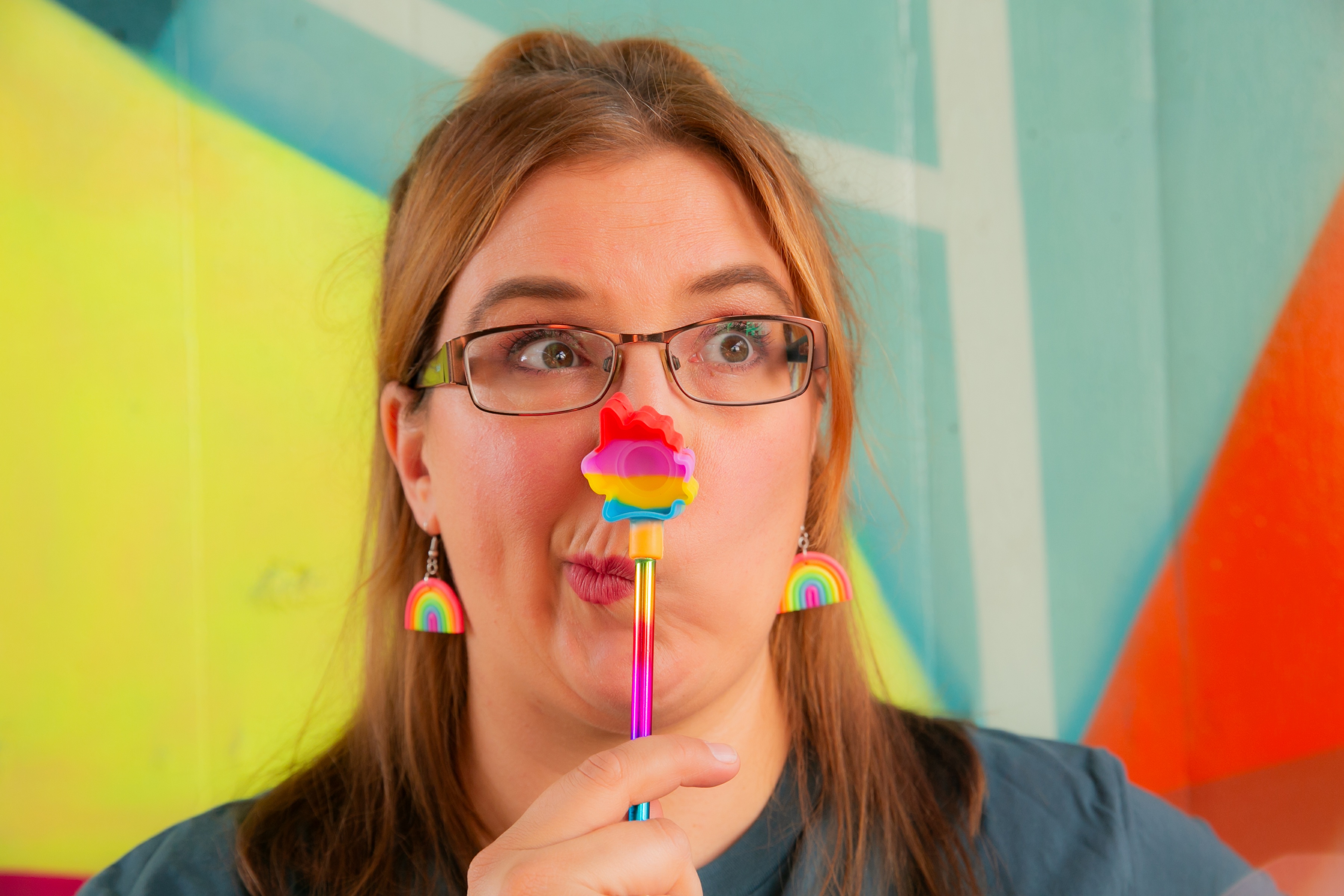 Rachel Clayton playfully holds a rainbow pen in front of her face while looking surprised. The image accompanies a personal reflection explaining that many neurodivergent people don't recognise burnout until they're already experiencing it deeply.