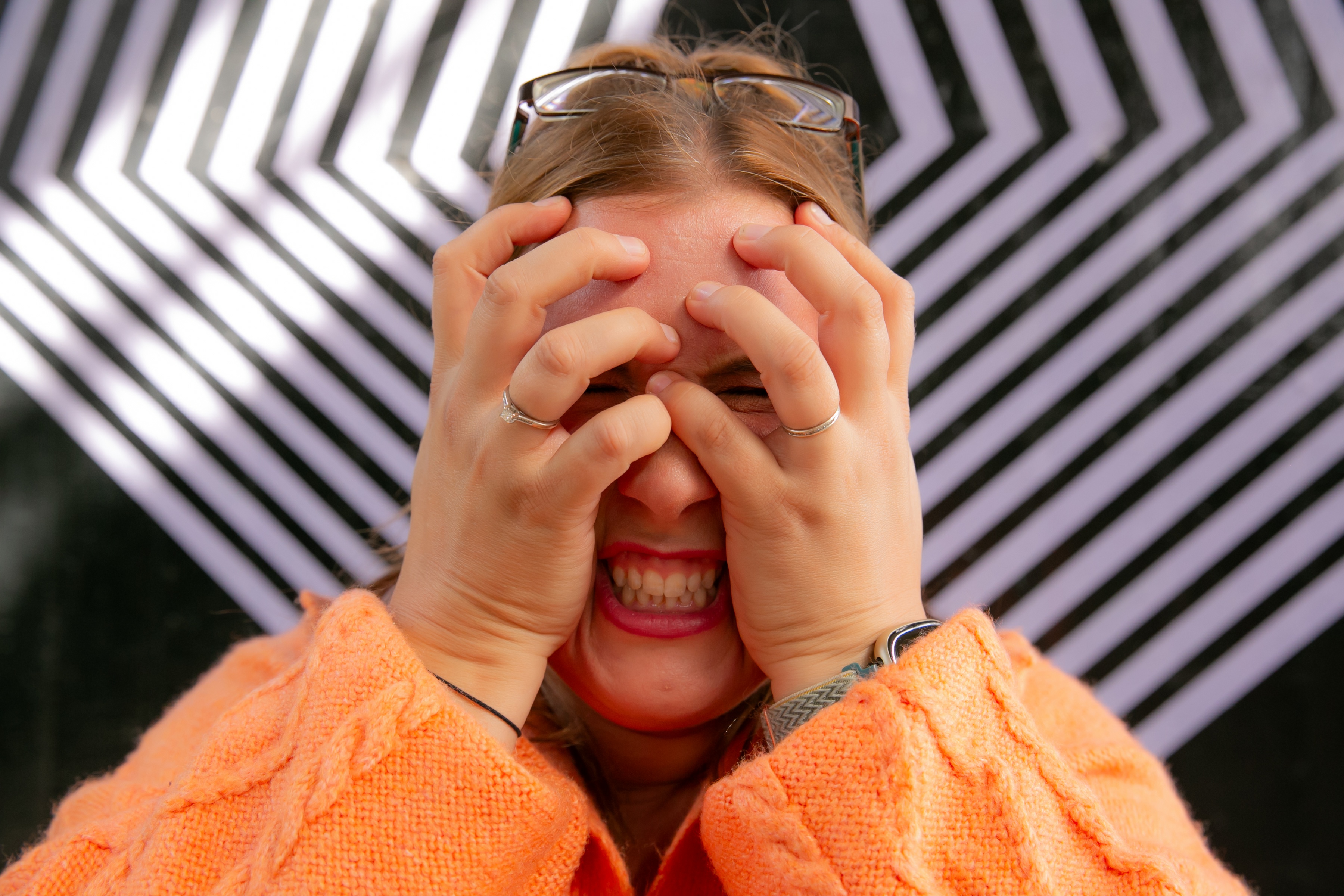 Rachel Clayton holds her head in her hands with a strained expression, representing the overwhelming stress and emotional exhaustion of neurodivergent burnout. The image accompanies her personal story of experiencing repeated burnout before recognising the signs and understanding the impact of chronic stress, masking and pushing through exhaustion.