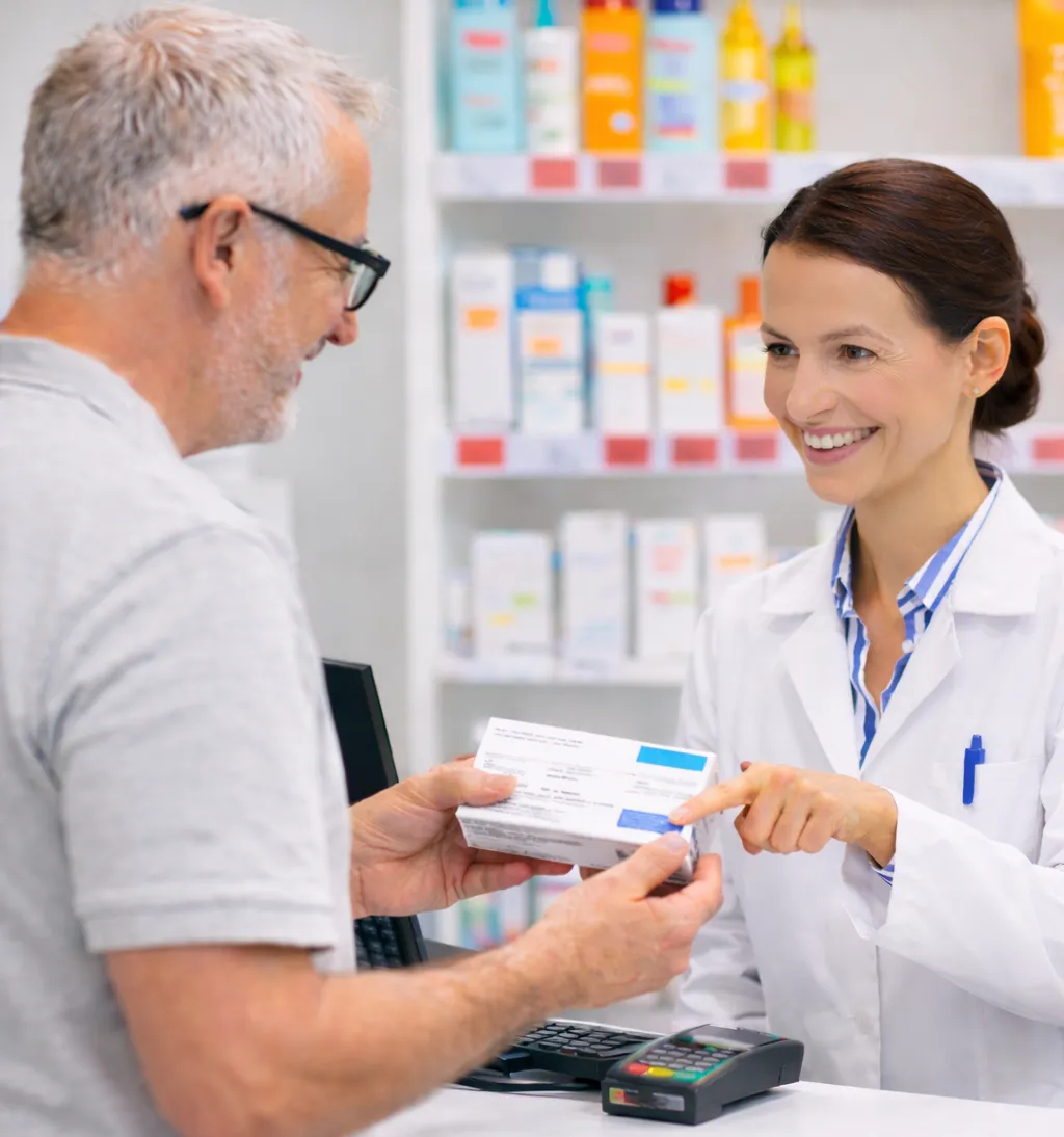 Eine Apothekerin steht in der DOC Meyer Apotheke und zeigt einem älteren Kunden auf einem Tablet Informationen an. Beide stehen vor Regalen mit Pflege- und Gesundheitsprodukten.