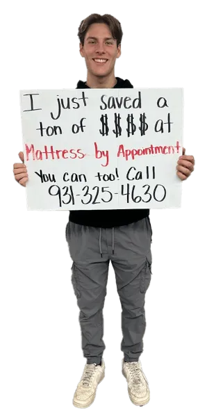 A picture of a happy guy that bought a mattress holding an "I love my new mattress" sign