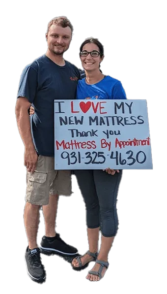 A picture of a happy couple that bought a mattress holding an "I love my new mattress" sign