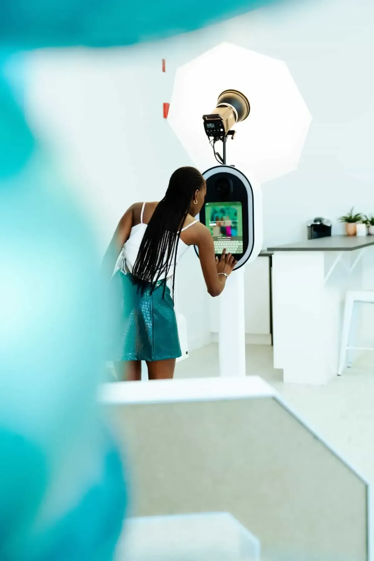 A person interacts with a touchscreen photo booth under studio lighting in a bright room, enjoying the dynamic features offered by the premier photo booths in DC, Maryland, and Virginia.