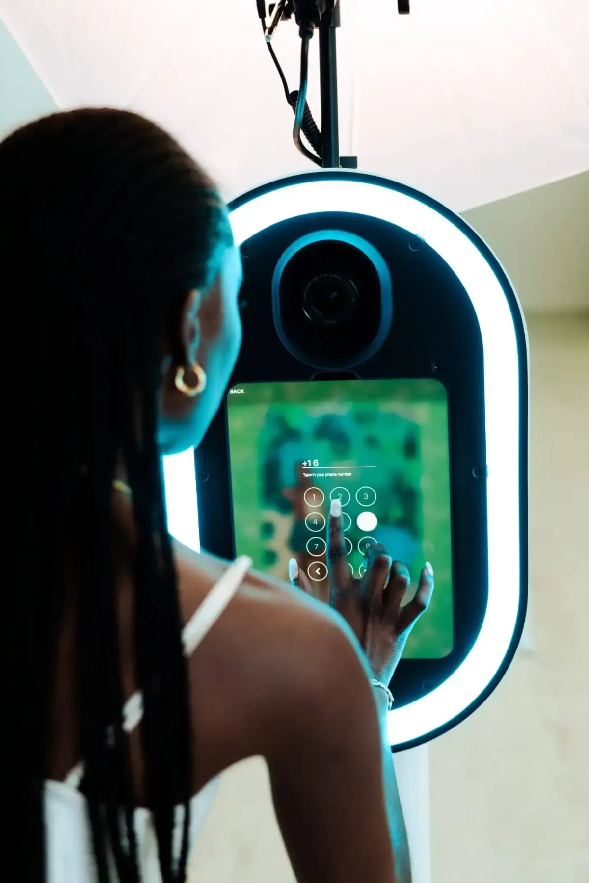 A person engages with a touchscreen interface on a neon-lit photo booth, captivated by the sharp, high image quality.