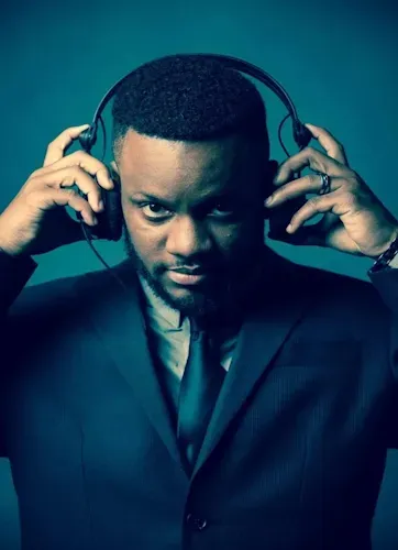 A man in a suit, perhaps a wedding DJ in Maryland, adjusts headphones on his head against a blue background.