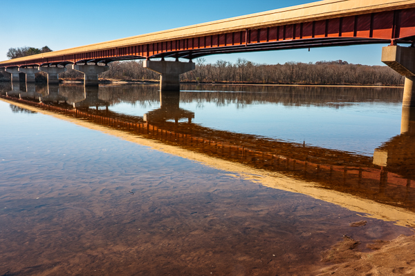 Highway bridge at Spring Green, Wisconsin, over the Wisconsin River, with the bridge reflecting off the calm surface waters under a blue sky in summer