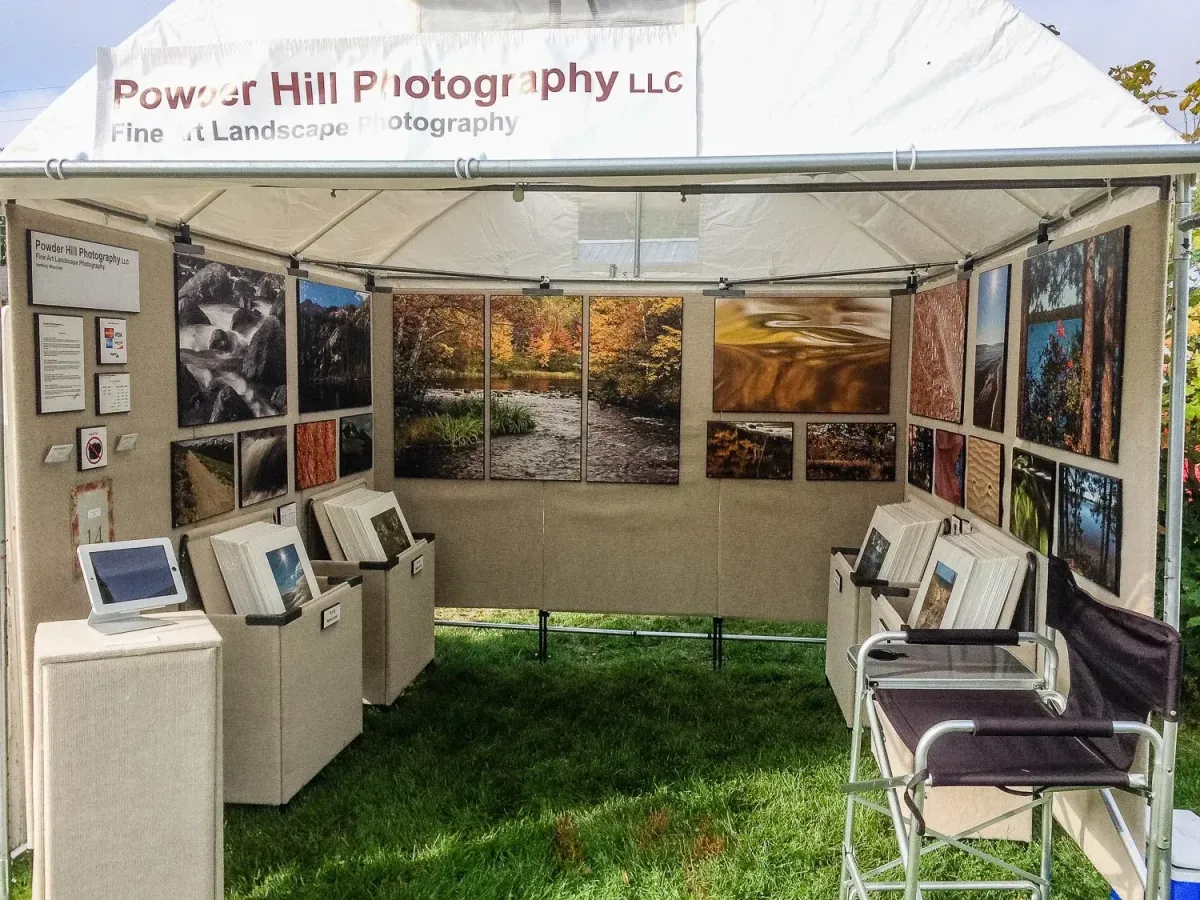 Image of the inside of an art fair booth, with prints displayed on walls and in print bins