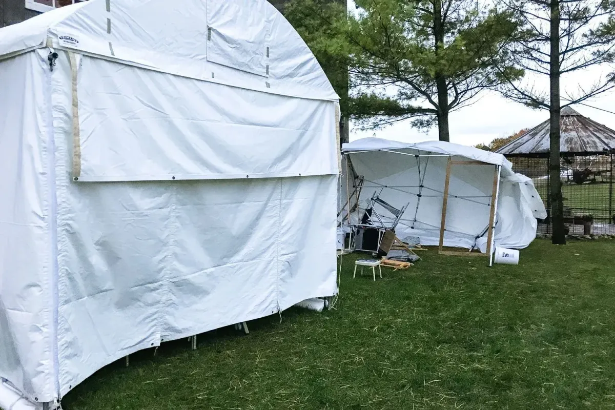At an art fair, a Trimline tent is standing whereas a lighter tent has been blown over in the wind
