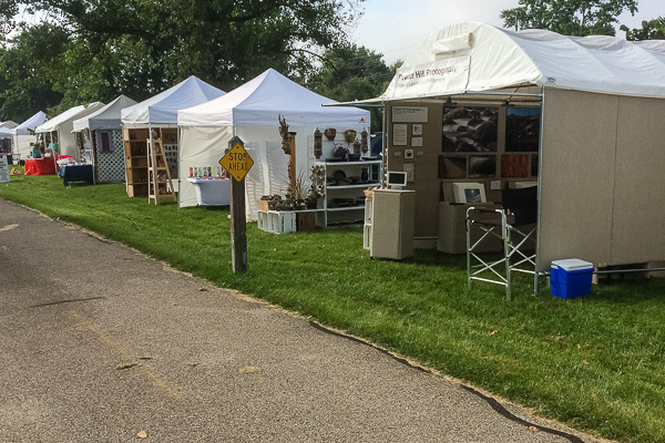 Art fair tents in a row at a show along a sidewalk