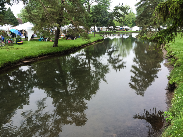 Art fair tents aligned along a quiet stream