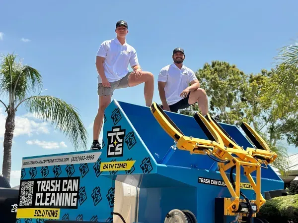 Trash can cleaning truck with team posing on top.