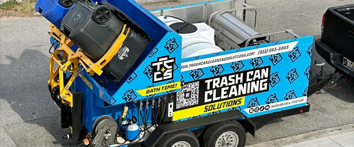 Trash can cleaning truck washing garbage bins using high-pressure water system.