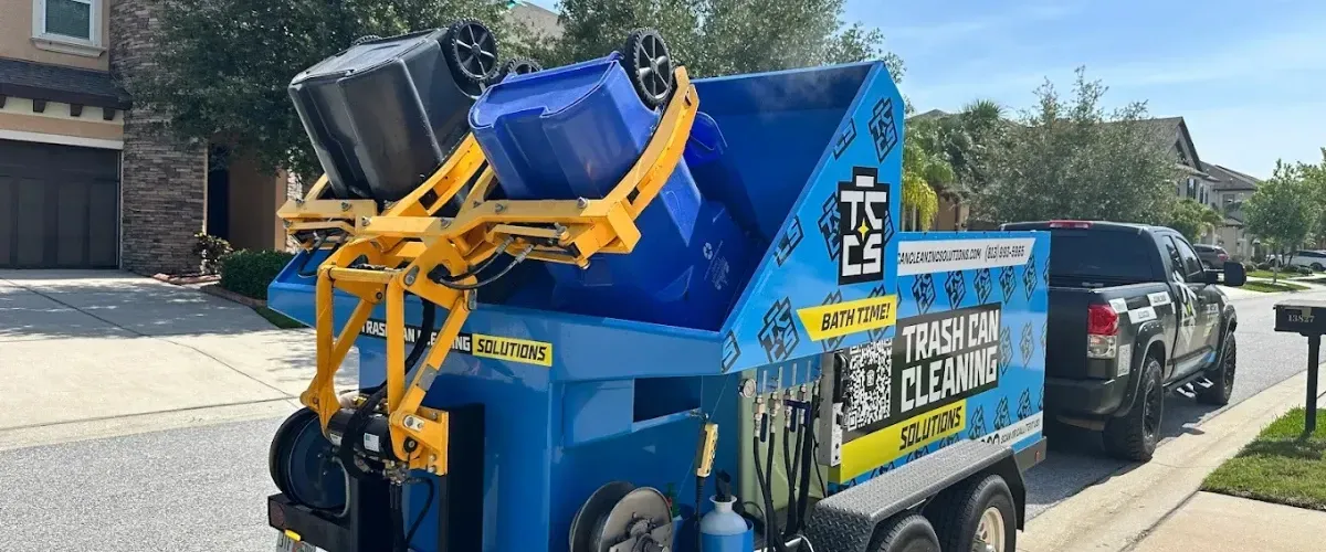 Automated trash bin cleaning truck washing garbage cans on residential street.