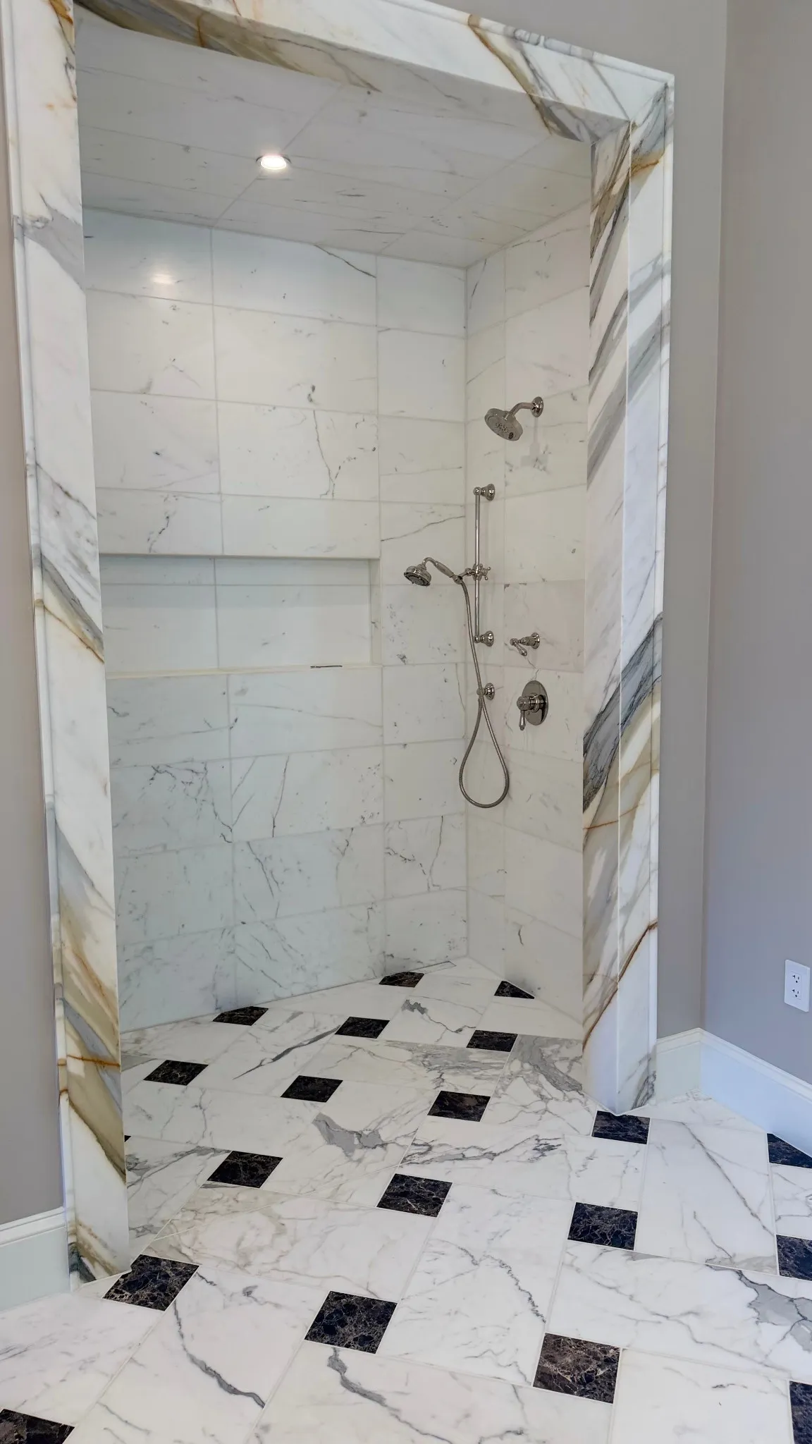 Marble-look shower alcove with long recessed niche and chrome fixtures