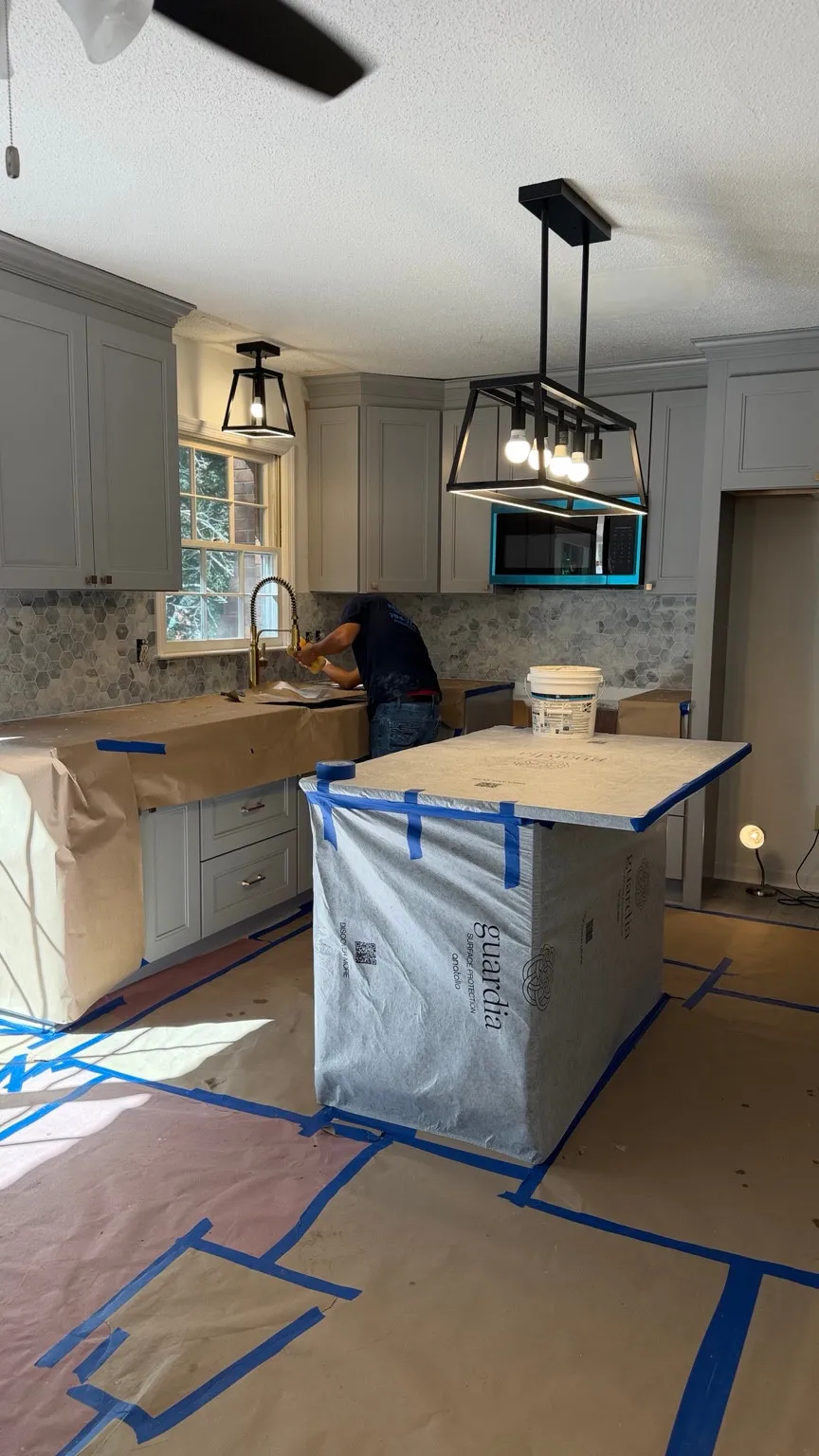 Kitchen work in progress with floors, counters and island covered for protection.